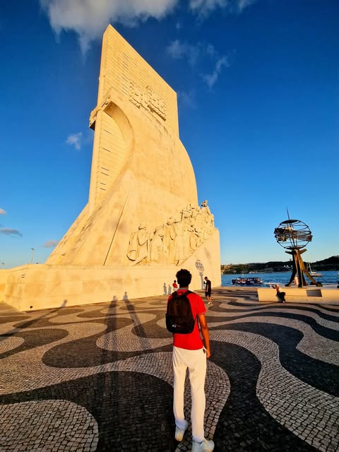 Jonathan standing beside a sculpted stone monument and patterned paving